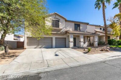 A front-facing view of a two-story home with a three-car garage, desert landscaping, and a welcoming front porch under a clear blue sky.