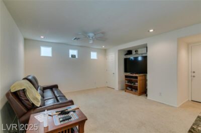 Carpeted living room with recessed lighting, ceiling fan, three square clerestory windows, and built-in TV niche at 7645 Interlace Street.